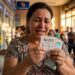 Mulher chorando de emoção segura bilhete da Loteria dos Sonhos com número 9759 e notas de dinheiro