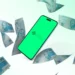 Smartphone com logo do Pix cercado por notas de 100 reais.