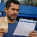 Trabalhador segurando notas de reais e consultando calendário, representando os pagamentos dos novos lotes do PIS/Pasep.
