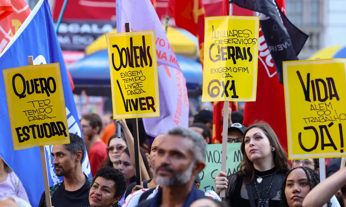 Manifestantes erguem cartazes amarelos pelo fim da escala 6x1 durante ato de rua.