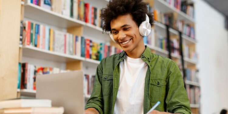 Estudante usando notebook e fones de ouvido enquanto aprende idiomas em uma biblioteca.