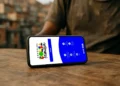 Celular sobre mesa de madeira exibindo tela inicial do aplicativo Bolsa Família com ícones de serviços