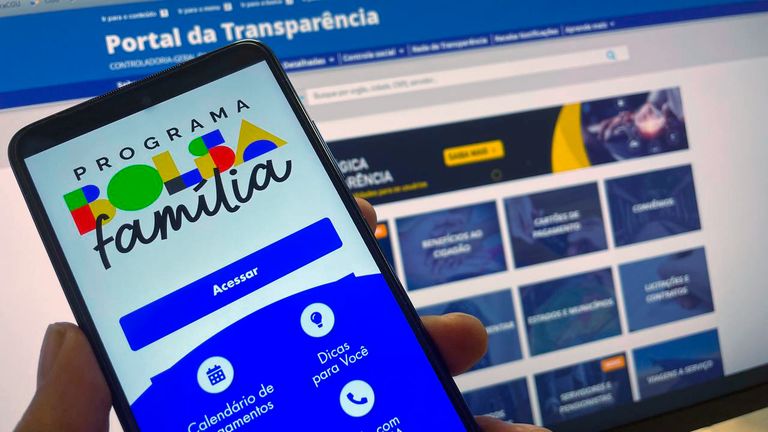 Tela de celular exibe o site do Bolsa Família com a logomarca do programa em destaque.