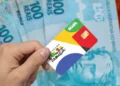 Cartão do Bolsa Família em frente a cédulas de dinheiro, representando o pagamento de maio com adicionais para beneficiários.