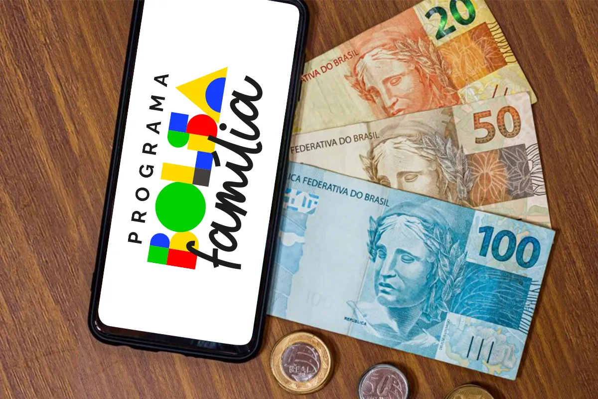 Smartphone exibindo logotipo do Programa Bolsa Família ao lado de cédulas e moedas brasileiras