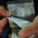 Mãos de pessoa contando cédulas de cem reais sobre fundo escuro