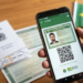 Mão segurando smartphone com app e-Título aberto, exibindo título digital com foto e QR Code, bandeira do Brasil ao fundo