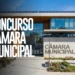 Prédio de Câmara Municipal com arquitetura contemporânea, fachada de vidro, painéis solares no telhado e jardim frontal.