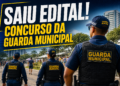 Agentes da Guarda Municipal com uniformes azuis e coletes patrulham a área externa com prédios ao fundo.