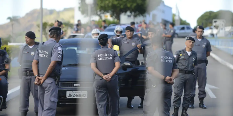 Policiais militares uniformizados em formação ao lado de viaturas durante operação ao ar livre