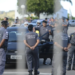 Policiais militares uniformizados em formação ao lado de viaturas durante operação ao ar livre