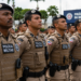 Soldados da PMBA perfilados usando uniforme bege com colete tático, boina preta e distintivos da bandeira da Bahia.
