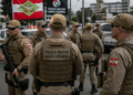 Policiais militares de Santa Catarina com coletes táticos cor cáqui e bonés em formação ao ar livre.