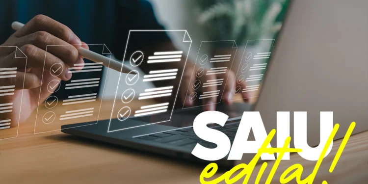 Mão segura caneta stylus sobre laptop com ícones de checklist digital e texto "SAIU edital!" em destaque.