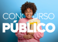 Jovem negra sorridente com cabelo afro, óculos e blusa rosa segura livros e documentos sobre fundo azul.
