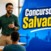 Professor negro com óculos e camisa verde leciona para alunos com palavras motivacionais no quadro e arte de Salvador ao fundo