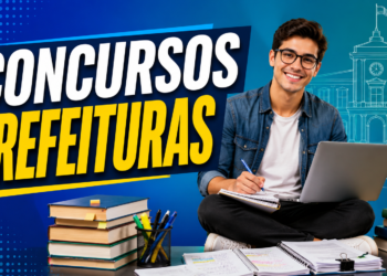 Jovem de óculos sentado estudando com notebook e livros ao redor para concursos de prefeituras