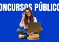 Jovem sorridente de óculos e camisa branca estuda com notebook sobre pilha de livros, fundo azul com texto Concursos Públicos