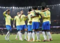 Jogadores da Seleção Brasileira comemoram gol abraçados em campo iluminado