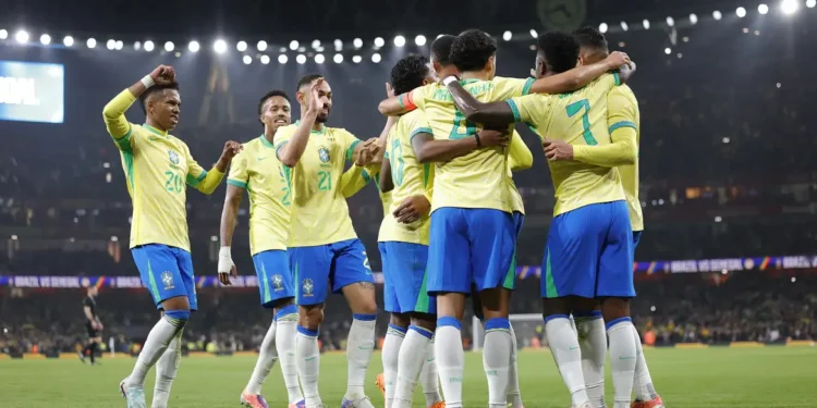 Jogadores da Seleção Brasileira comemoram gol abraçados em campo iluminado