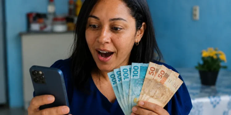Mulher segurando dinheiro enquanto consulta informações no celular, representando o pagamento residual do FGTS.