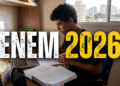 Jovem de cabelos cacheados estuda em mesa com livros, cadernos, notebook e texto "ENEM 2026" sobreposto.