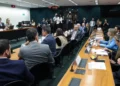 Parlamentares reunidos em torno de mesa durante sessão de comissão na Câmara dos Deputados.
