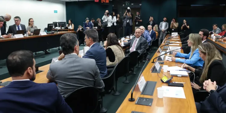 Parlamentares reunidos em torno de mesa durante sessão de comissão na Câmara dos Deputados.