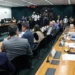 Parlamentares reunidos em torno de mesa durante sessão de comissão na Câmara dos Deputados.