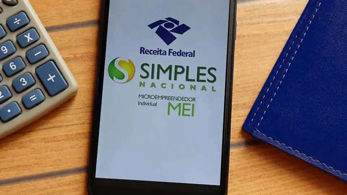 Tela de computador com portal do Simples Nacional ao fundo e smartphone em primeiro plano exibindo a logo da Receita Federal