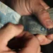 Mãos contando notas de cem reais durante quitação de dívidas pelo Desenrola Brasil