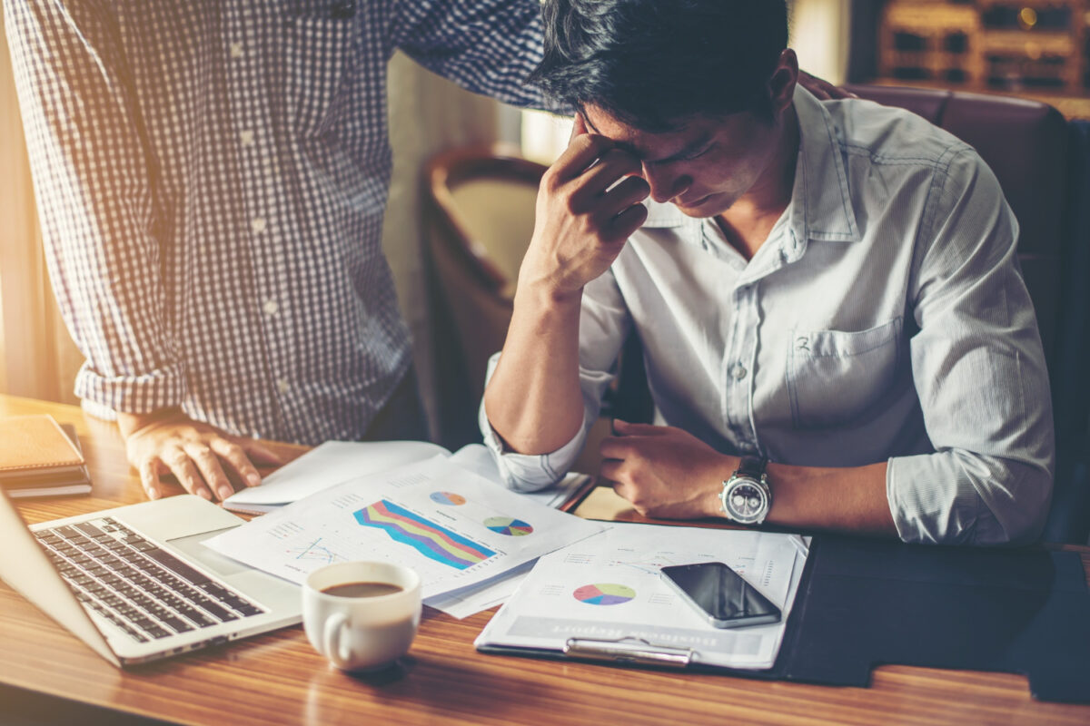 Empresário com expressão preocupada em escritório enquanto analisa relatórios financeiros sobre a mesa