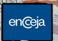 Mãos segurando tablet com logotipo do Encceja em destaque sobre cartão de inscrição e folha de redação