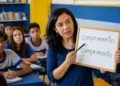 Professora em sala de aula mostrando em um quadro a diferença entre as palavras “comprimento” e “cumprimento” para alunos.