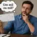 Homem segurando cheque e pensando se o correto é escrever “um mil” ou “mil”.