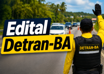 Agente do DETRAN-BA com camisa amarela e colete preto sinalizando parada para veículos em rodovia