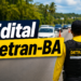 Agente do DETRAN-BA com camisa amarela e colete preto sinalizando parada para veículos em rodovia