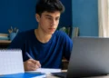 Estudante brasileiro atento diante do notebook, representando o acompanhamento da abertura das inscrições do Enem 2026.