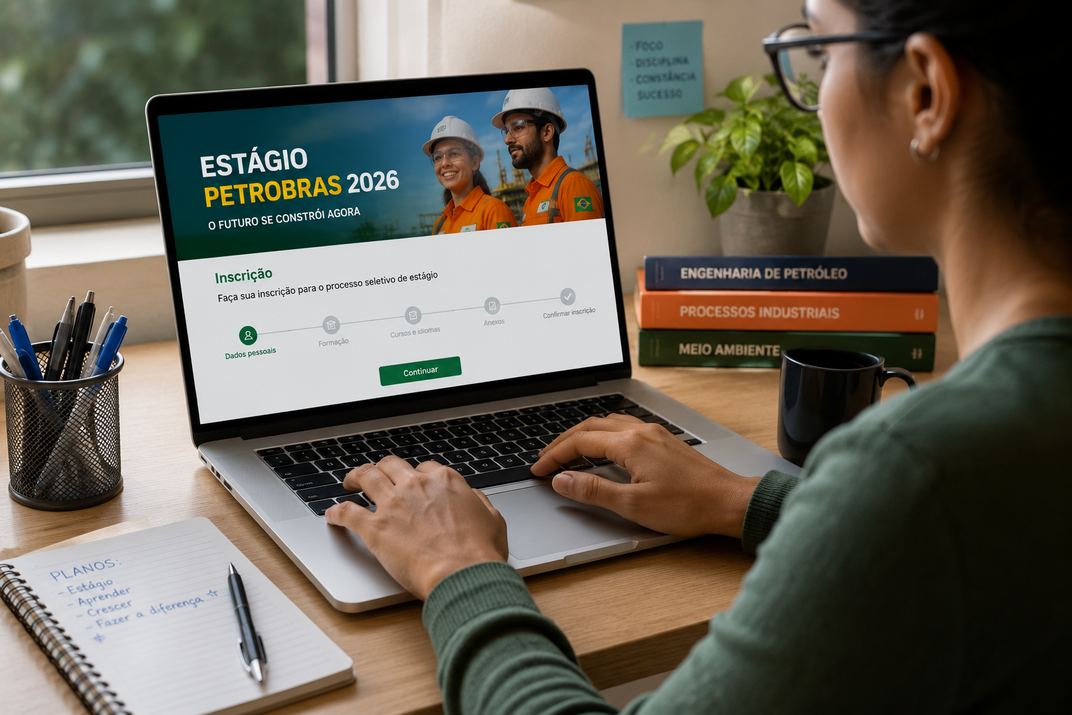 Jovem de óculos e blusa verde digita no notebook mostrando tela do Estágio Petrobras 2026, com livros de engenharia ao lado.