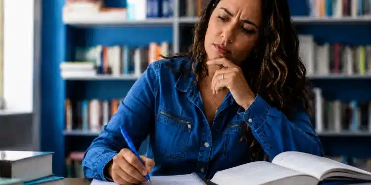Mulher adulta escrevendo em caderno com expressão de dúvida, representando o uso correto de "incluso" e "incluído.