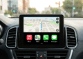 Painel de carro exibindo Apple CarPlay com mapa 3D de navegação e ícones de Music, Maps, Phone e Mensagens.