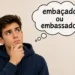 Homem pensativo com balão de pensamento perguntando se o correto é embaçado ou embassado.