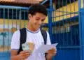 Estudante da rede pública segurando documentos do Enem 2026 e cédulas de dinheiro, representando a gratuidade do exame e o bônus de R$ 200.