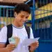 Estudante da rede pública segurando documentos do Enem 2026 e cédulas de dinheiro, representando a gratuidade do exame e o bônus de R$ 200.