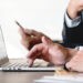Empresário utilizando notebook e celular para consultas digitais em ambiente corporativo