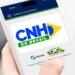 Mão segura um smartphone que exibe a tela inicial do aplicativo CNH do Brasil, plataforma oficial do Ministério dos Transportes e do Serpro para o processo de habilitação no país.