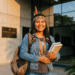 Estudante indígena sorri segurando livros em frente ao prédio da Universidade Federal Indígena
