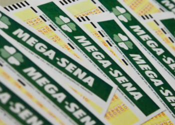 Vários volantes da Mega-Sena empilhados exibindo logo verde e amarelo das Loterias Caixa