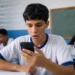 Estudante consultando o celular em sala de aula, representando mensagem do MEC sobre a terceira parcela do programa Pé-de-Meia.