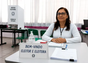 Mesária voluntária em seção eleitoral aguardando eleitores para atendimento nas eleições de 2026